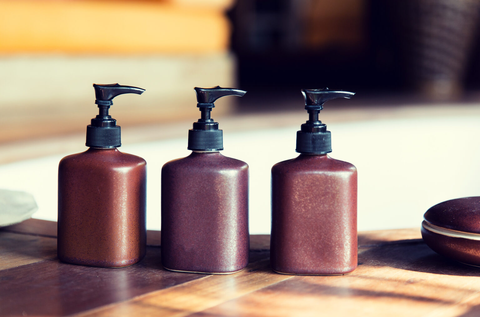 beauty, body care, luxury and hygiene concept - close up of liquid soap or body lotion set at hotel bathroom